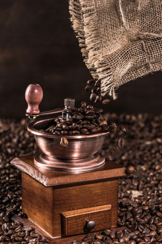 pouring coffee beans into a coffee mill